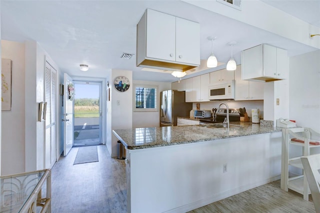 kitchen featuring stainless steel refrigerator with ice dispenser, white cabinetry, decorative light fixtures, light hardwood / wood-style floors, and kitchen peninsula