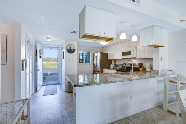3310 Loveland Blvd Unit 2304, Punta Gorda, FL 33980 - kitchen featuring appliances with stainless steel finishes, a peninsula, light wood finished floors, stone counters, and white cabinetry