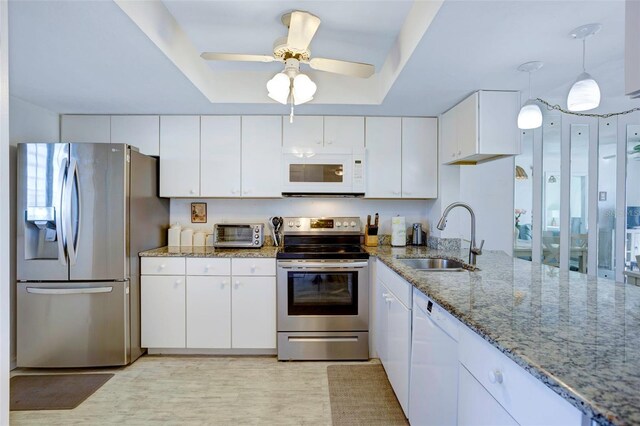 3310 Loveland Blvd Unit 2304, Punta Gorda, FL 33980 - kitchen with stainless steel appliances, a sink, a tray ceiling, white cabinetry, and light stone counters