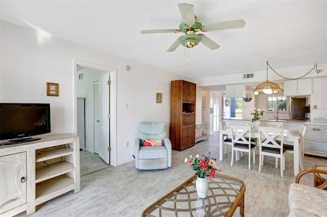 living room featuring ceiling fan, sink, and light hardwood / wood-style flooring