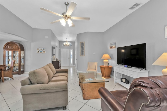 tiled living room with ceiling fan with notable chandelier and high vaulted ceiling