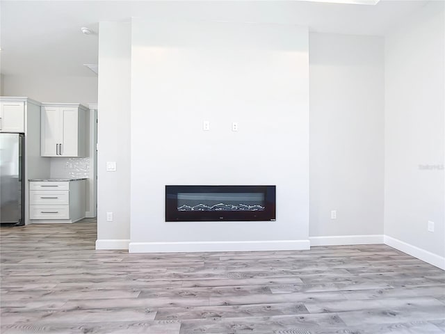 interior details with wood-type flooring, stainless steel refrigerator, and tasteful backsplash