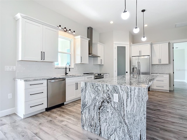 kitchen featuring white cabinets, wall chimney range hood, light hardwood / wood-style floors, a kitchen island, and stainless steel appliances