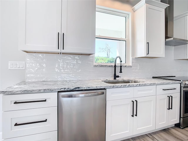 kitchen featuring white cabinetry, sink, wall chimney exhaust hood, light stone counters, and appliances with stainless steel finishes