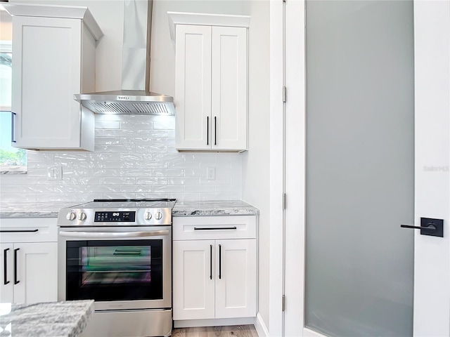 kitchen with white cabinets, stainless steel electric range, light stone counters, and wall chimney range hood