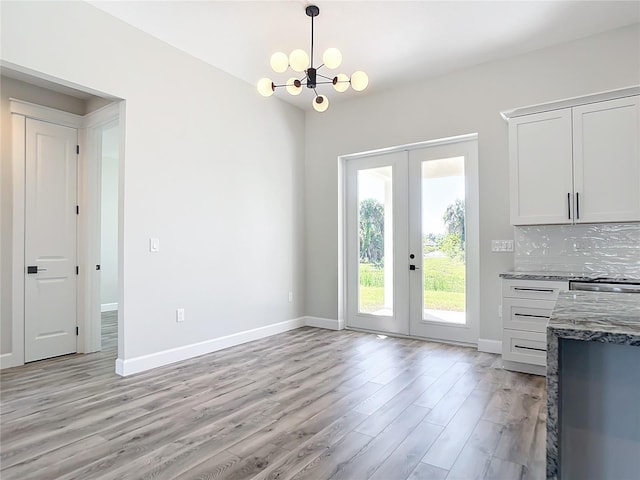 doorway to outside featuring french doors, light wood-type flooring, and an inviting chandelier