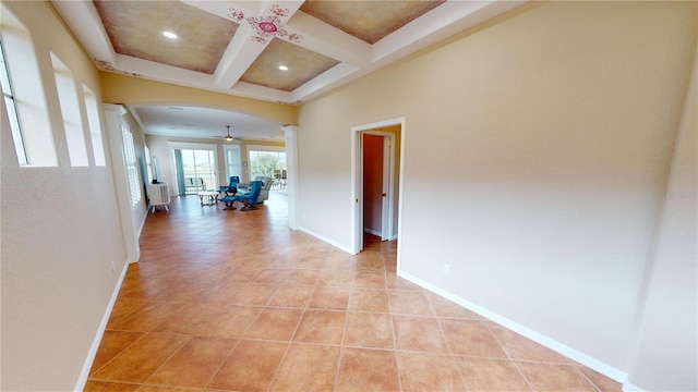 hallway with beamed ceiling, light tile patterned floors, and coffered ceiling