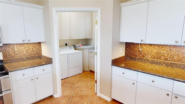 laundry area with cabinets, light tile patterned floors, and washing machine and clothes dryer