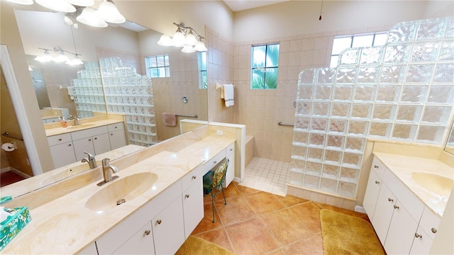 bathroom featuring tile patterned floors, plenty of natural light, a tile shower, and vanity