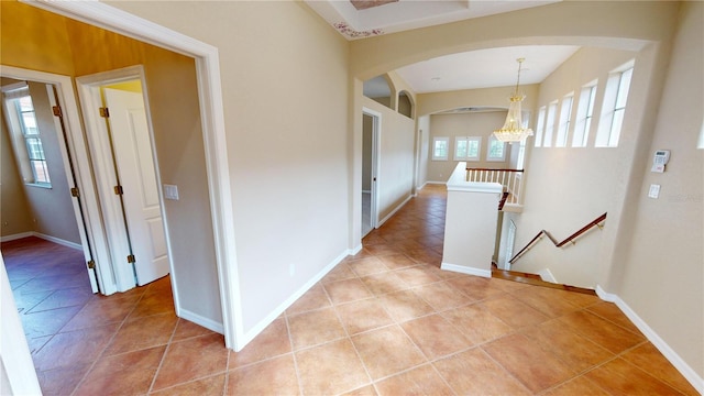 corridor with light tile patterned floors and a notable chandelier