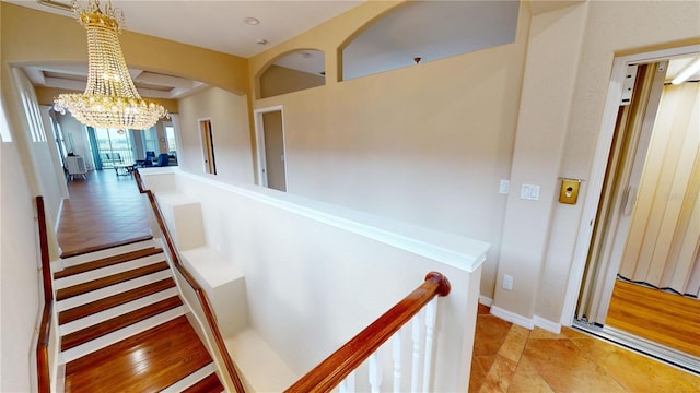 stairway featuring hardwood / wood-style floors and a notable chandelier