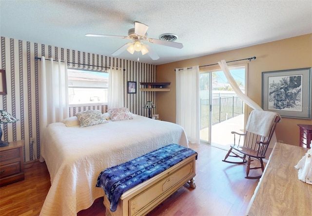 bedroom with access to outside, multiple windows, hardwood / wood-style flooring, and ceiling fan