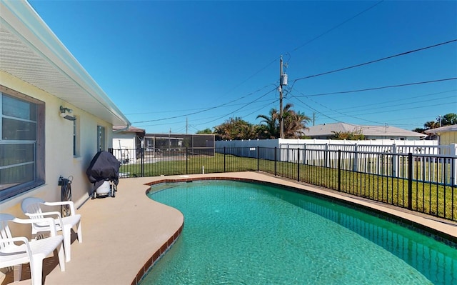 view of swimming pool featuring a lawn, a patio area, and grilling area