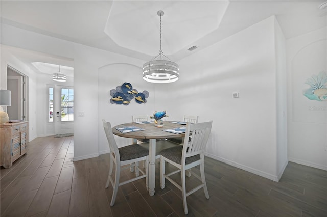 dining room with a chandelier, dark hardwood / wood-style floors, and a tray ceiling