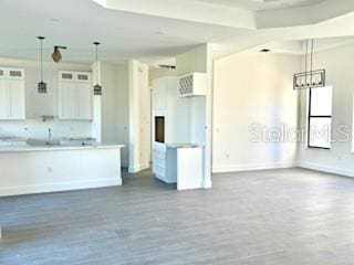 kitchen with wood-type flooring, white cabinetry, and hanging light fixtures