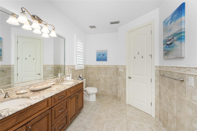 bathroom featuring toilet, tile patterned floors, vanity, and tile walls