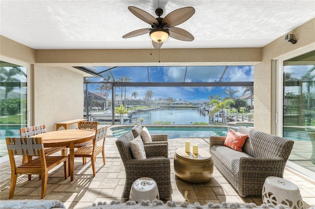 sunroom with ceiling fan and a water view