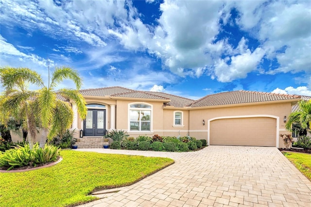 mediterranean / spanish home featuring french doors, a garage, and a front lawn