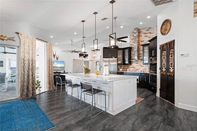 kitchen featuring decorative light fixtures, a spacious island, decorative backsplash, stainless steel appliances, and wall chimney exhaust hood