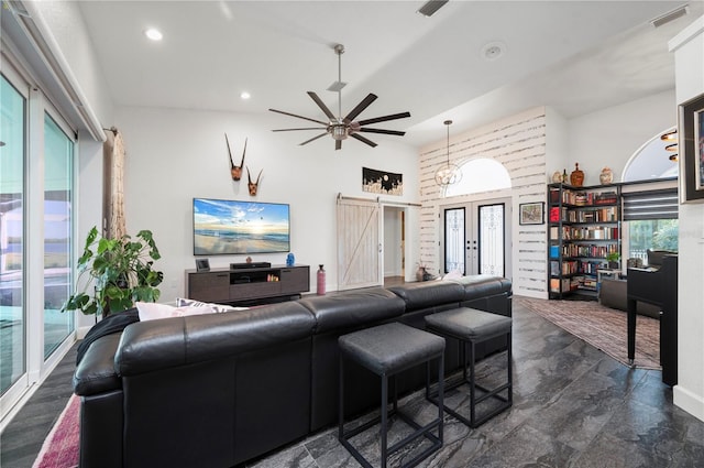 living room with ceiling fan, a barn door, and french doors