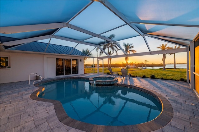 pool at dusk with a lanai, a patio, and an in ground hot tub