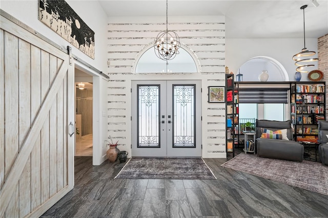 foyer entrance with dark wood-type flooring, a barn door, french doors, and a notable chandelier