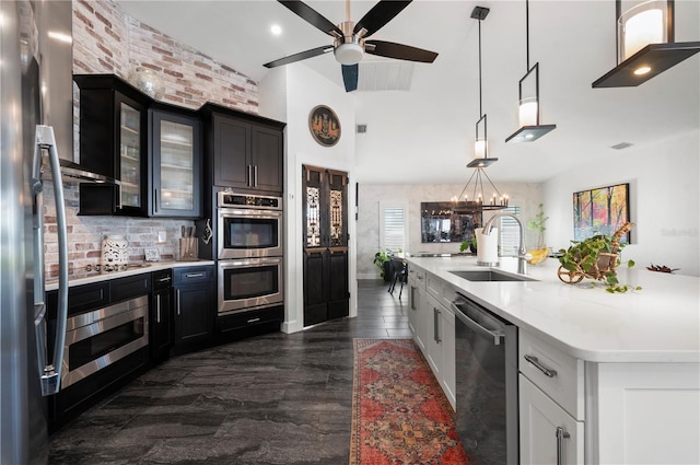 kitchen featuring backsplash, pendant lighting, a center island with sink, sink, and appliances with stainless steel finishes