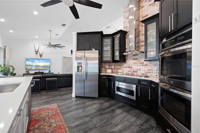 kitchen with vaulted ceiling, decorative backsplash, stainless steel appliances, white cabinets, and wall chimney exhaust hood