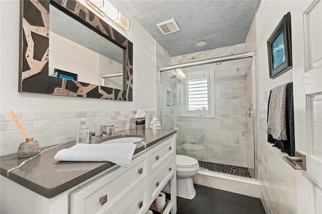 bathroom featuring a textured ceiling, toilet, vanity, and walk in shower