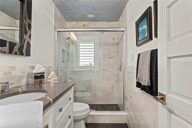 bathroom with toilet, a textured ceiling, an enclosed shower, and vanity