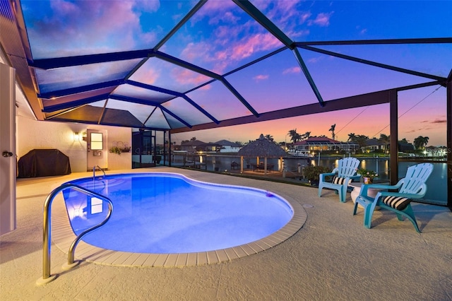 pool at dusk featuring an outdoor pool, a lanai, a water view, and a patio