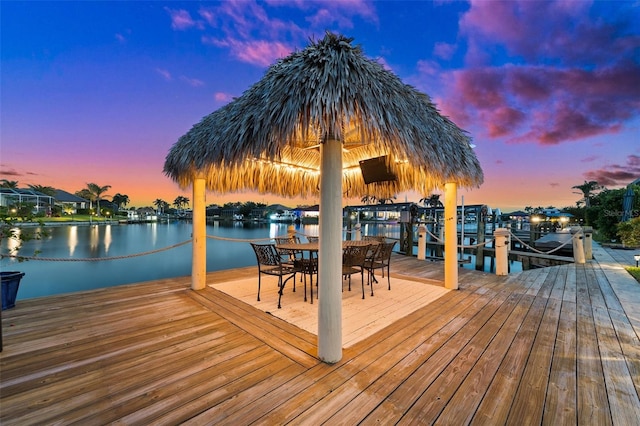 view of dock featuring outdoor dining space, a water view, and boat lift