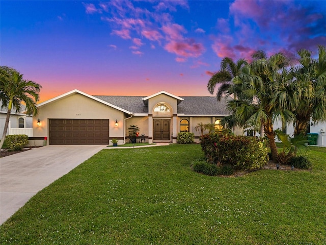 ranch-style home with an attached garage, a shingled roof, driveway, stucco siding, and a front lawn