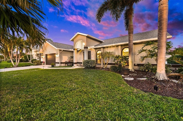 view of front of home featuring an attached garage, driveway, a front yard, and stucco siding