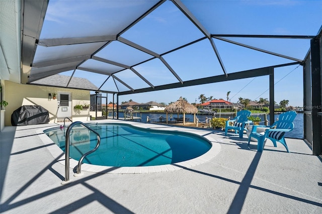 pool featuring glass enclosure, a water view, and a patio