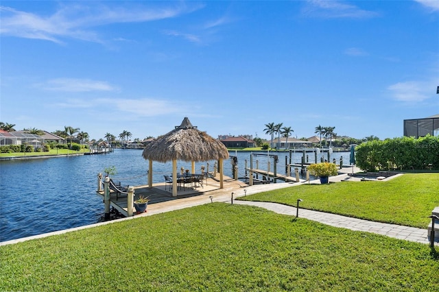 view of dock with a water view, a lawn, and a gazebo