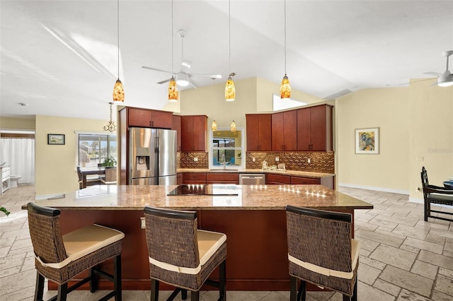 kitchen featuring tasteful backsplash, stone tile floors, a ceiling fan, stainless steel appliances, and a sink