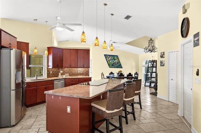 kitchen featuring appliances with stainless steel finishes, a breakfast bar, stone tile flooring, and a center island