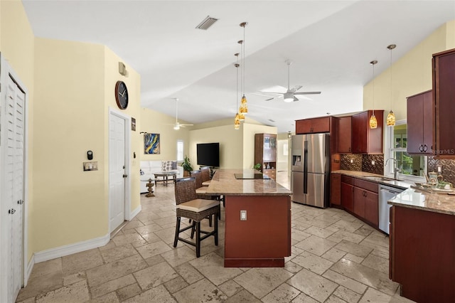 kitchen with a kitchen breakfast bar, open floor plan, dark brown cabinets, appliances with stainless steel finishes, and stone tile flooring