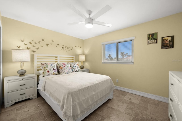 bedroom featuring stone finish floor, ceiling fan, and baseboards