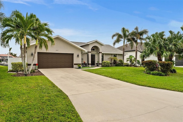 ranch-style home with a garage, concrete driveway, a front lawn, and stucco siding