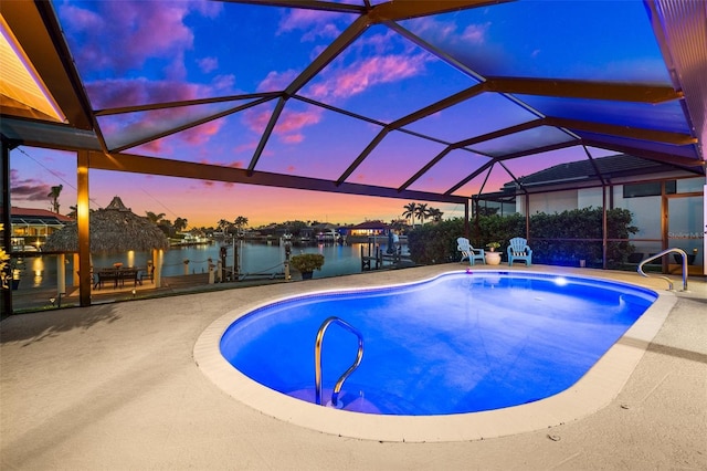 outdoor pool featuring a patio area, glass enclosure, a water view, and a dock