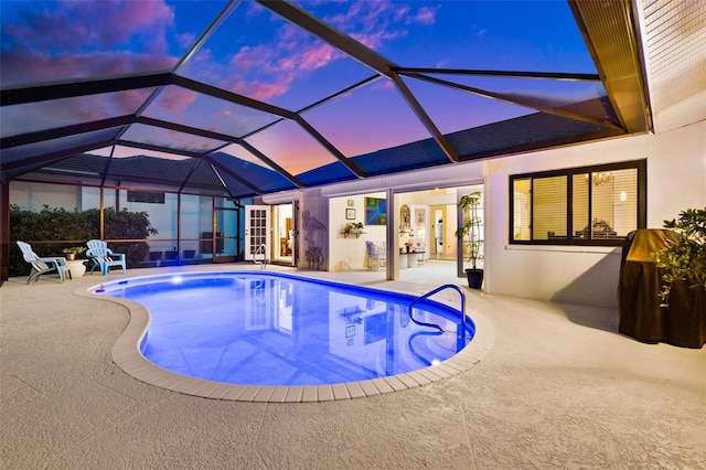 pool at dusk featuring a lanai, a patio area, and an outdoor pool