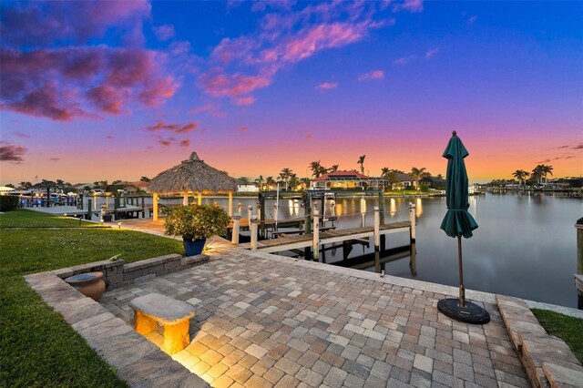 view of dock with a water view, a yard, boat lift, and a gazebo