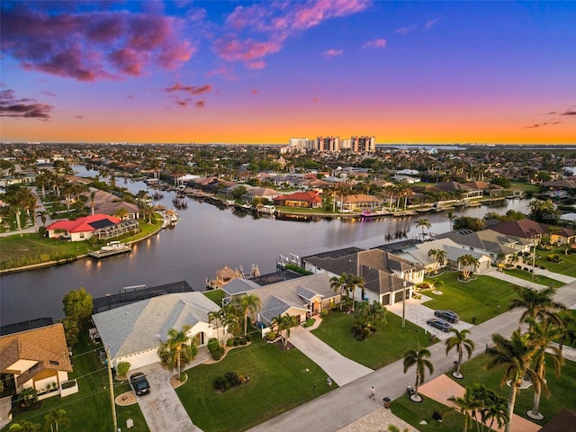 aerial view at dusk with a residential view and a water view