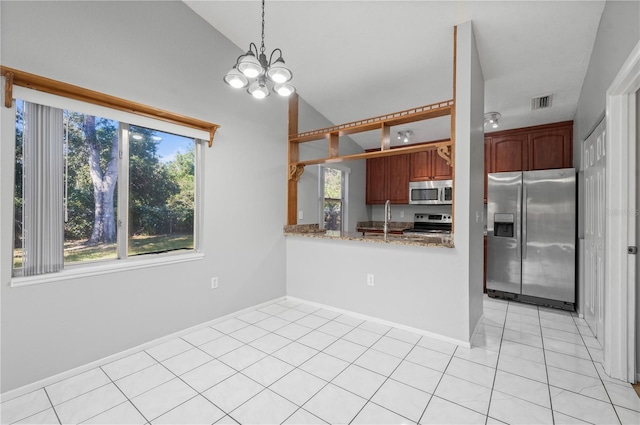 kitchen featuring kitchen peninsula, an inviting chandelier, stainless steel appliances, light tile patterned floors, and light stone counters