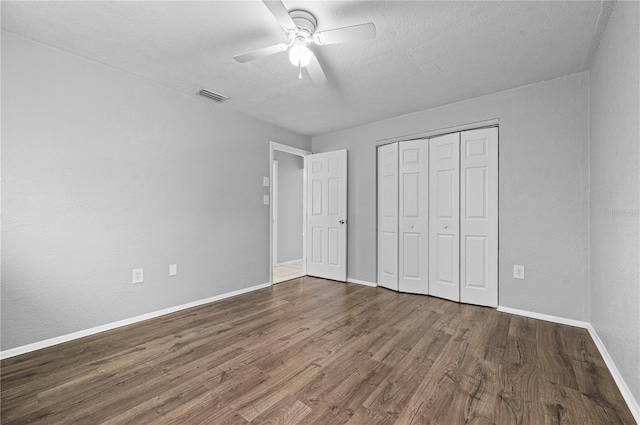 unfurnished bedroom with ceiling fan, a closet, dark hardwood / wood-style floors, and a textured ceiling