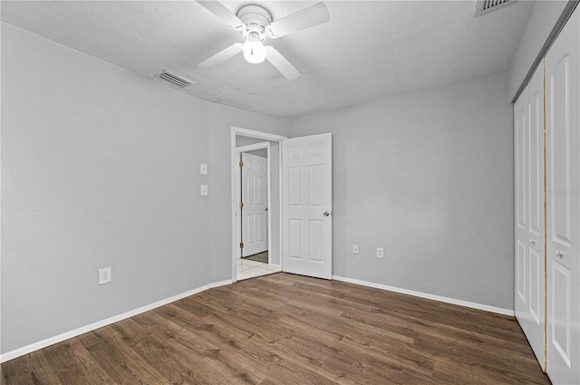 unfurnished bedroom featuring a textured ceiling, ceiling fan, a closet, and wood-type flooring