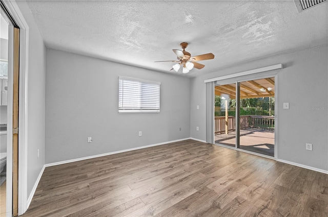 empty room with ceiling fan, a textured ceiling, and hardwood / wood-style floors