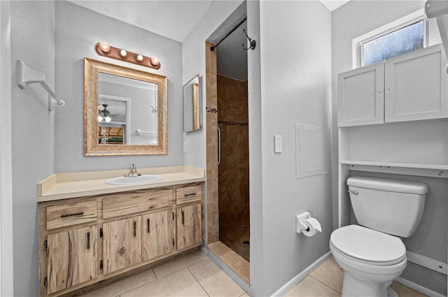 bathroom with toilet, vanity, a tile shower, and tile patterned flooring